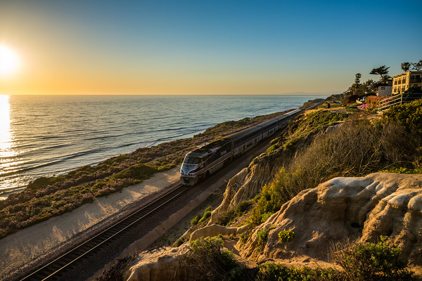 Photo of a sunset off the coast of Del Mar with a train passing by.