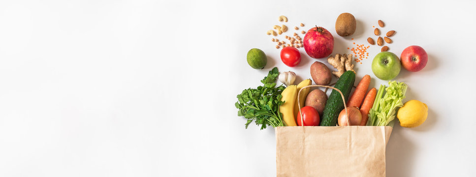 A photo of various produce items spilling out of the top of a grocery bag.