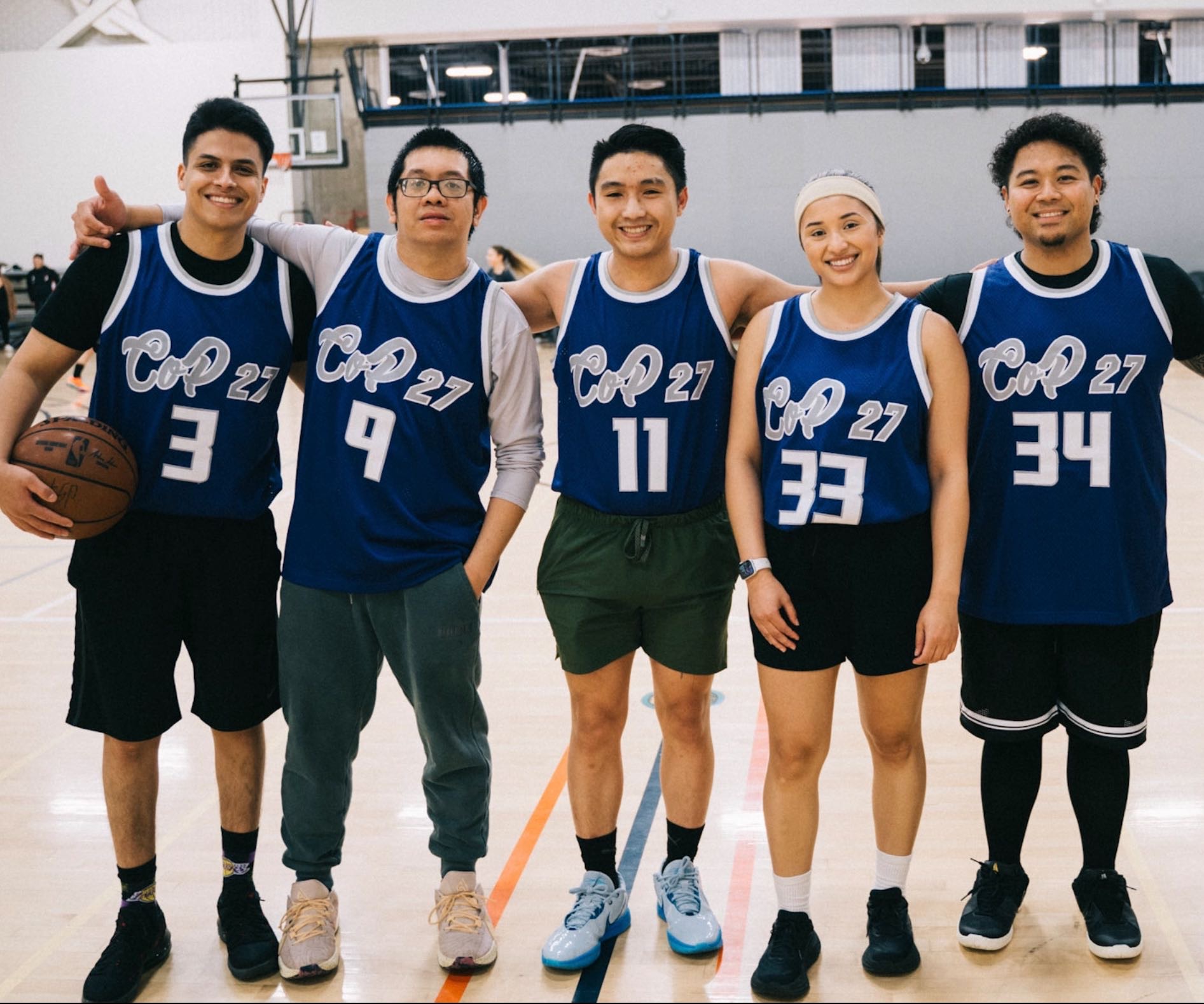 A group of students standing together on a basketball court with matching jerseys