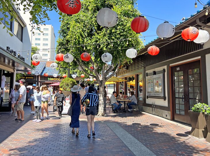 Photo of people walking down a brick street lined with red and white paper lanterns in Little Tokyo, Los Angeles.