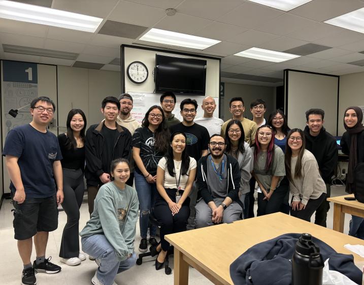 A photo of students standing together and smiling in a classroom.