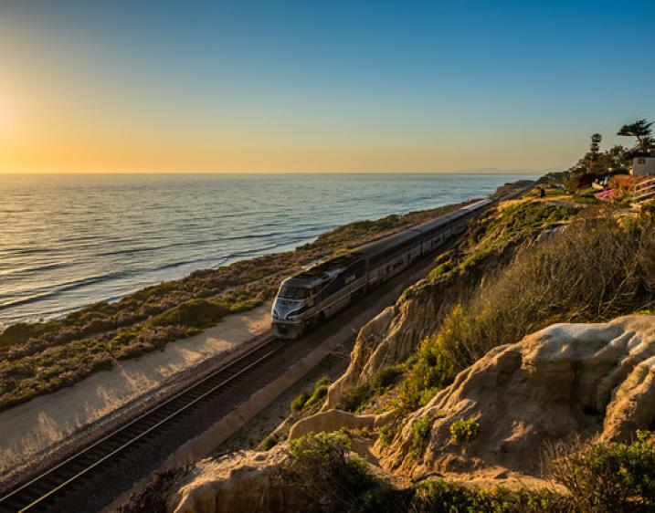 Photo of a sunset off the coast of Del Mar with a train passing by.