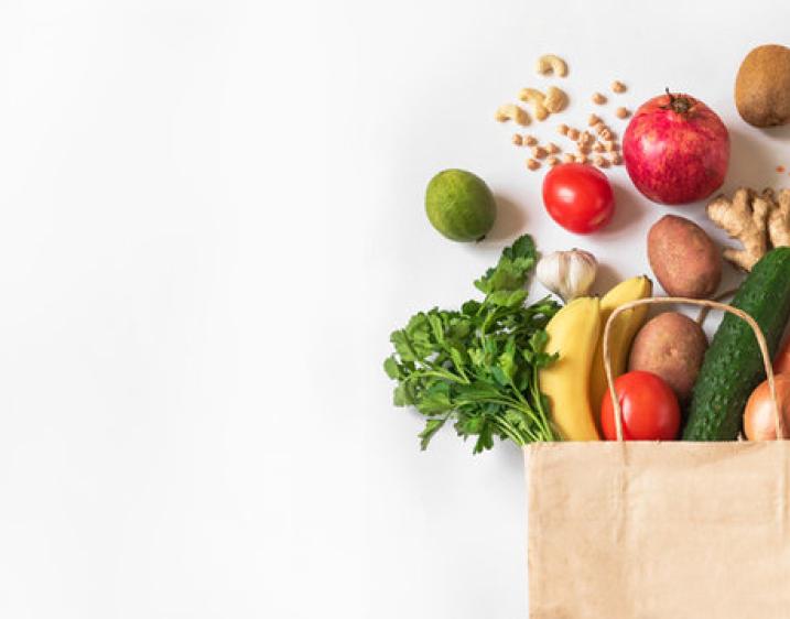 A photo of various produce items spilling out of the top of a grocery bag.